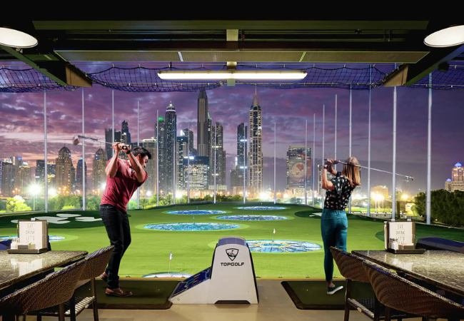 Top Golf Dubai driving bays facing the Marina skyline at dusk
